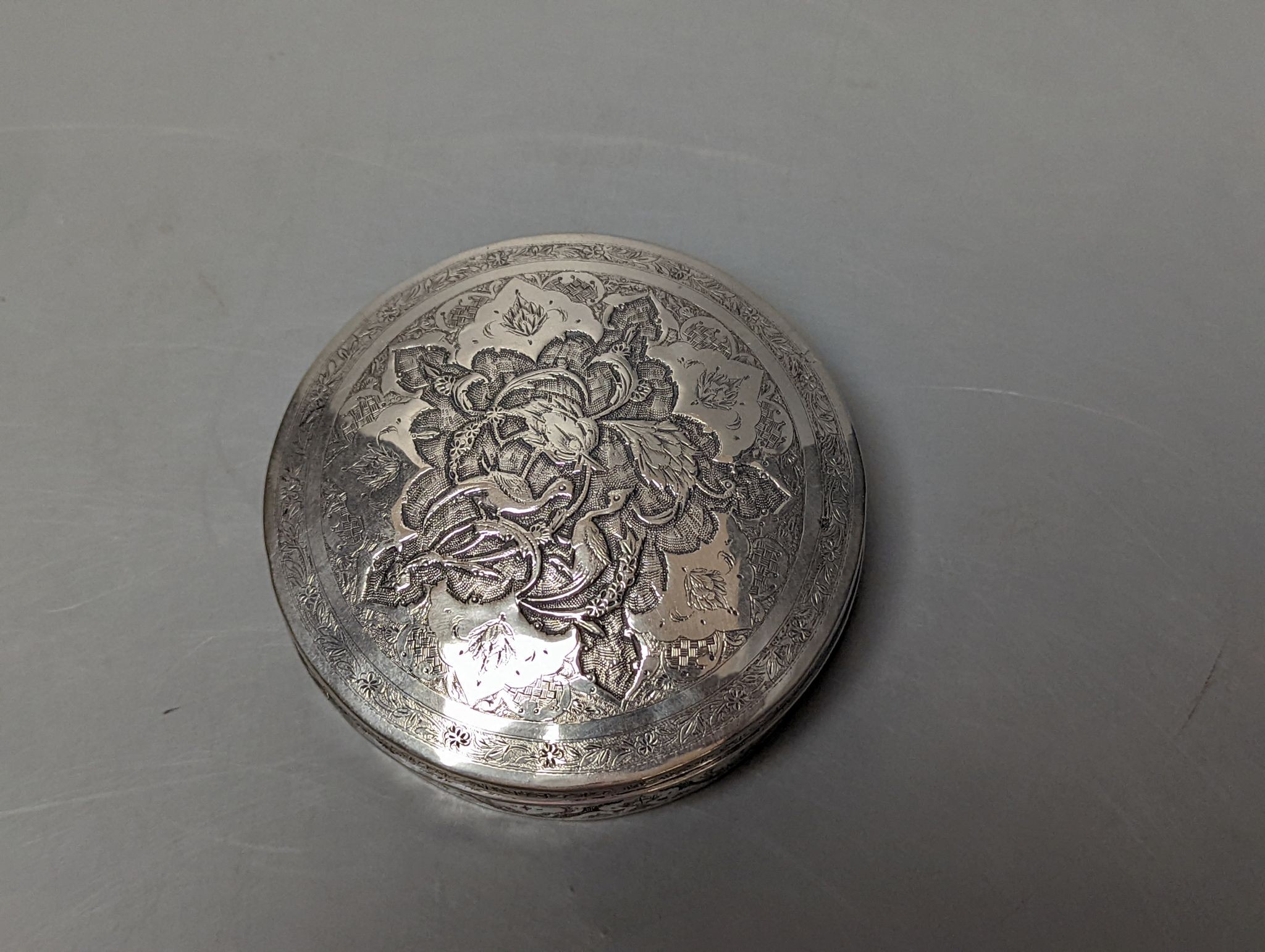 A Persian engraved white metal circular box and cover, 86mm
